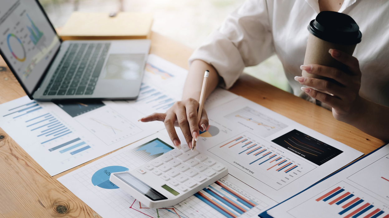 Close up Business woman using calculator and laptop for do m